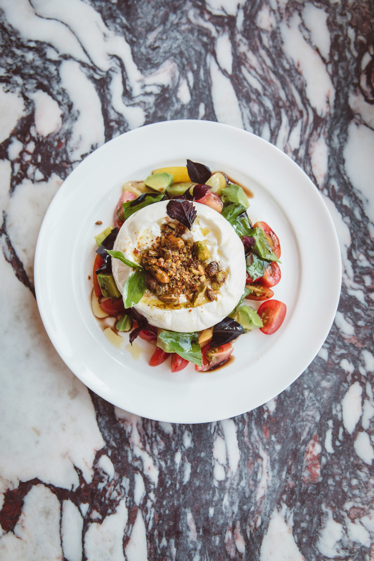 fresh burrata on a bed of tomatoes and lettuce